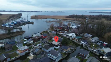 Luftaufnahme der Siedlung am See mit vielen Häusern und Bootsanlegestellen.