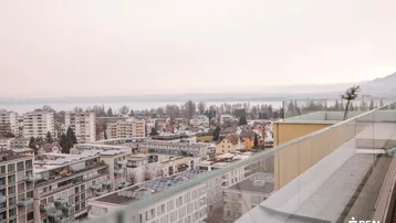 Balkon mit Glasbrüstung bietet einen weiten Blick über die Stadt und den See.