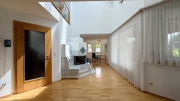 Helles Wohnzimmer mit hohen Decken, Parkettboden und Kamin.