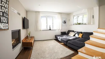 Gemütliches Wohnzimmer mit großem Sofa, Kamin und Holzboden.
