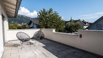 Geräumige Dachterrasse mit modernen Sitzgelegenheiten und Bergblick.