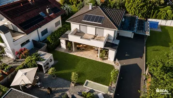 Weitläufige Luftaufnahme des Hauses mit großem Garten, Terrasse und umliegender grüner Landschaft.