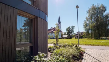 Seitenansicht des Gebäudes mit Blick auf eine Kirche und sonnige Grünflächen.