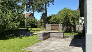 Geräumige Holzterrasse im Garten, ideal für Entspannung und Mahlzeiten im Freien.