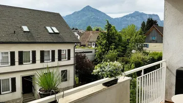 Balkon mit Bergblick und Blick auf die umliegenden Häuser und viel Grün.