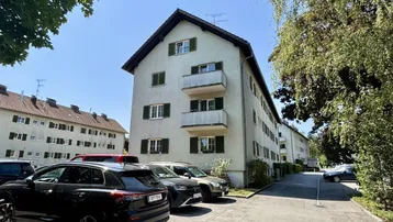 Mehrfamilienhaus mit mehreren Balkonen und gepflegter Außenanlage in sonniger Umgebung.