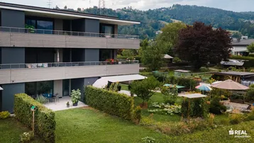 Mehrfamilienhaus mit Balkonen und gepflegtem Gartenbereich im Grünen.