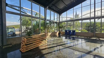Große, lichtdurchflutete Halle mit Glasfassade, dunklem Steinboden und Blick ins Grüne.