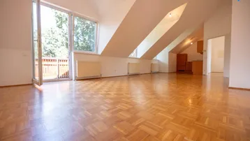 Helles Wohnzimmer mit Parkettboden, Dachschrägen und Zugang zu einem Balkon.