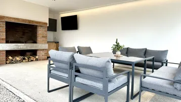 Geräumige überdachte Terrasse mit Außenküche, Grillbereich und Sitzgelegenheiten.