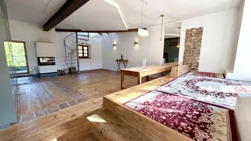 Geräumiger Wohnbereich mit Holzdielenboden, Kamin, Wendeltreppe und Sitzgelegenheiten.