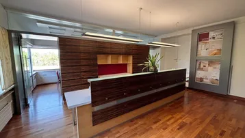 Empfangsbereich eines Büros mit dunklem Holzdesign, Holzboden und Blick in weitere Arbeitsräume.