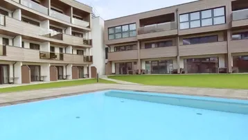 Außenansicht eines modernen Gebäudekomplexes mit Pool und Grünflächen.