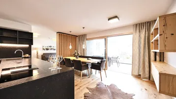 Moderner offener Wohn-Essbereich mit integrierter Küche, Holzboden und Zugang zur Terrasse.