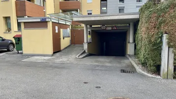 Eingang zur Tiefgarage mit angrenzendem Wohngebäude und Briefkästen in moderner Architektur.