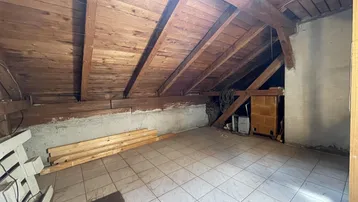 Geräumiger Dachboden mit sichtbaren Holzbalken, Holzdecke und Fliesenboden, bereit für Ausbau.