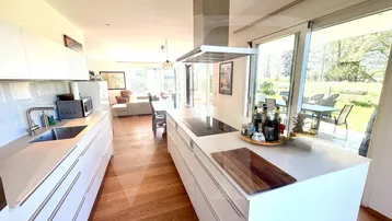 Moderne offene Küche mit Kochinsel, Induktionskochfeld und direktem Zugang zur Terrasse.