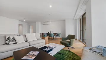 Geräumiger, offener Wohn- und Essbereich mit modernem Design, Holzboden und Zugang zum Balkon.