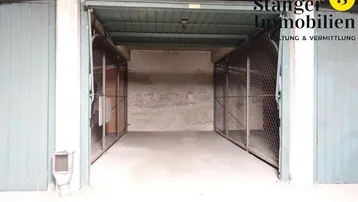Blick in eine Tiefgarage mit offenen Garagentoren zu den einzelnen Stellplätzen und Betonwänden.