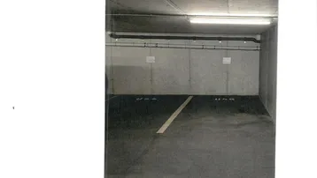 Tiefgarage mit Betonwänden und -decke, beleuchtet von Leuchtstoffröhren, zeigt einen einzelnen Parkplatz.