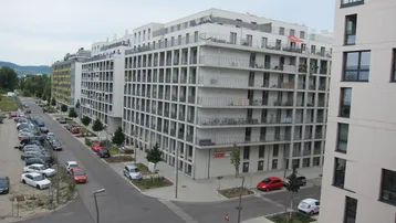 Moderne Wohngebäude mit zahlreichen Balkonen und Parkplätzen in einer städtischen Umgebung.