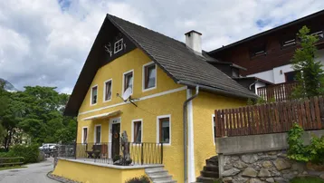Gelbes Haus mit Satteldach und traditioneller Architektur in ländlicher Umgebung.