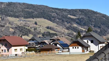 Panoramablick auf die umliegende Berglandschaft mit mehreren Wohnhäusern.