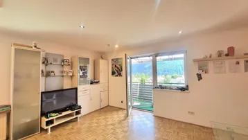 Wohnzimmer mit Parkettboden, TV-Möbeln und Zugang zu einem Balkon mit Bergblick.