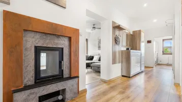 Geräumiger Flur mit modernem Kamin und Holzfußboden, der zum Wohnbereich führt.