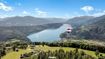 Atemberaubender Panoramablick auf den See und die umliegende Berglandschaft unter blauem Himmel.