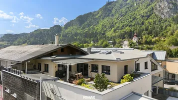 Luftaufnahme des modernen Gebäudes mit Dachterrasse und Bergblick.