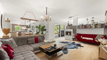 Gemütliches Wohnzimmer mit Holzboden, Kamin und bequemen Sofas, offen zum Essbereich.