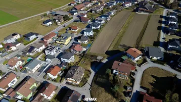Panoramablick aus der Luft auf eine dichte Wohnbebauung neben landwirtschaftlich genutzten Feldern.
