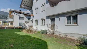Außenansicht des Gebäudes mit gepflegtem Rasen und einem kleinen Gartenbereich im Vordergrund.
