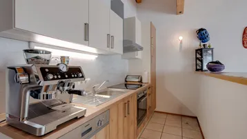 Moderne Küche mit hellen Schränken, Holzarbeitsplatte und integrierten Geräten unter Holzbalkendecke.