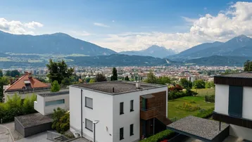 Modernes Wohnhaus mit Flachdach und Carport, gelegen mit weitem Blick über die Stadt und Berge.