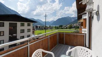 Heller Balkon mit Sitzgelegenheiten und weitem Blick auf den See und die Berge.