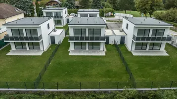 Moderne Reihenhäuser mit Flachdächern und privaten Gärten in einer Wohnsiedlung.