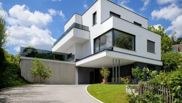 Modernes Einfamilienhaus mit klaren Linien, Flachdach und großzügiger Auffahrt.