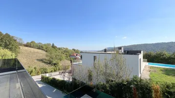 Weitläufiger Blick von der Terrasse auf die grüne Hügellandschaft und den Poolbereich.