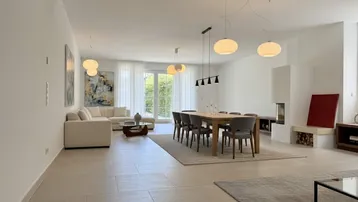 Geräumiger, lichtdurchfluteter Wohn-Essbereich mit modernem Kamin und Zugang zum Außenbereich.