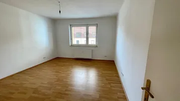 Heller, unmöblierter Raum mit Laminatboden, weiß gestrichenen Wänden und einem Fenster.