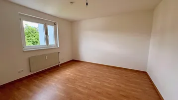 Helles Zimmer mit Laminatboden und Blick ins Grüne, ideal als Schlaf- oder Arbeitszimmer.