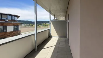 Langer Balkon mit Fliesen und weitem Blick über Felder und die hügelige Landschaft.