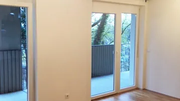 Helles Zimmer mit Parkettboden und Zugang zu zwei Balkonen, ideal für Wohn- oder Schlafbereich.