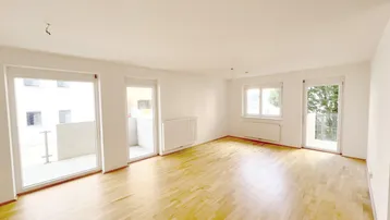 Helles, leeres Wohnzimmer mit Parkettboden und Zugang zu zwei Balkonen, ideal für individuelle Gestaltung.