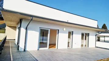 Moderne Neubauwohnung mit großer gefliester Terrasse und Zugang zu den Innenräumen.