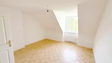 Helles Zimmer mit Dachschrägen und Parkettboden, ideal als Schlaf- oder Wohnbereich nutzbar.
