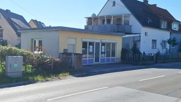 Ansicht des Hauses und des Nebengebäudes von der Straße aus an einem sonnigen Tag.