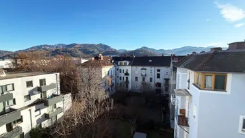 Panoramablick über die Stadt mit Bergen im Hintergrund unter klarem blauem Himmel.